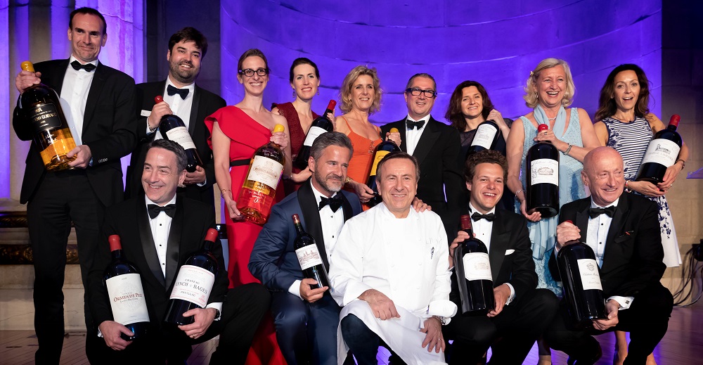 Group of people on stage holding bottles of wine